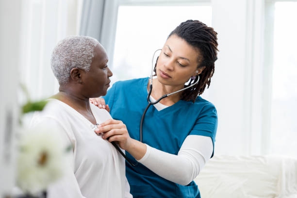 Female home healthcare providers checks patient's vital signs A caring mid adult female home healthcare nurse uses a stethoscope to check the heart and lungs on a senior female patient. listening to heartbeat stock pictures, royalty-free photos & images