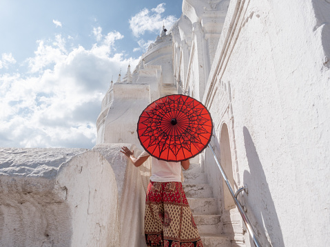Woman holding traditional red umbrella exploring Mingun ancient temple in Mandalay