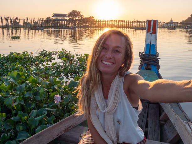 Woman takes selfie at sunset at U being bridge from long tail boat Young woman traveling in Asia, taxi boat
Woman enjoys sunset at U being bridge from long tail boat u bein bridge stock pictures, royalty-free photos & images