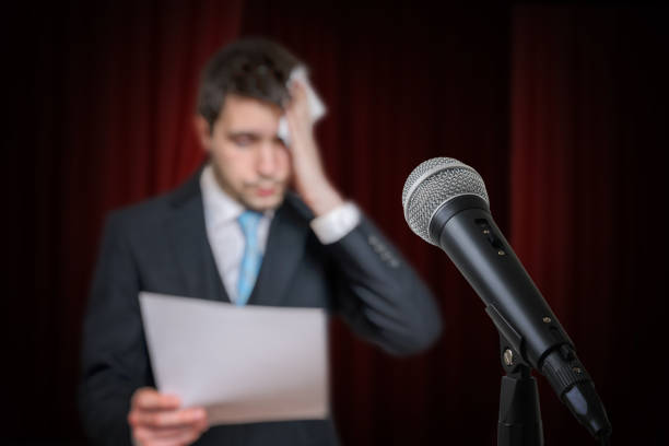 istock Nervous speaker is afraid of public speech and is sweating. Microphone in front. 1280554783