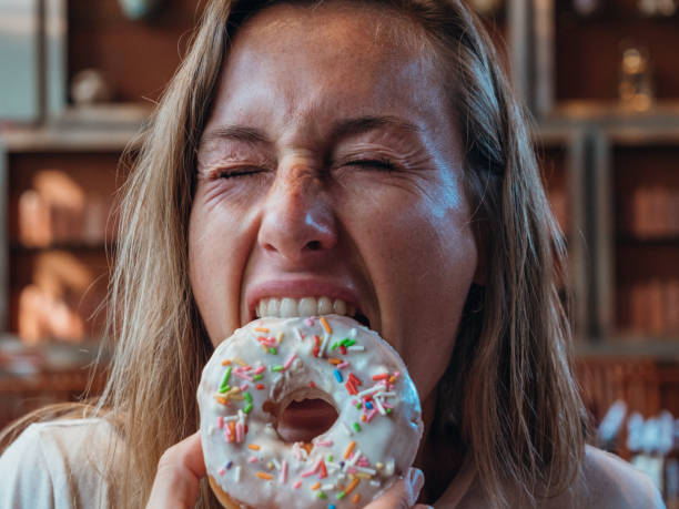 istock Woman eating unhealthy doughnut 1280554827
