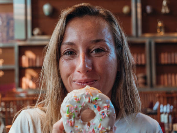 istock Woman eating unhealthy doughnut 1280554900