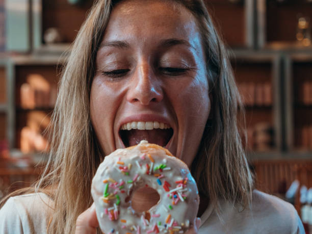 istock Woman eating unhealthy doughnut 1280555058