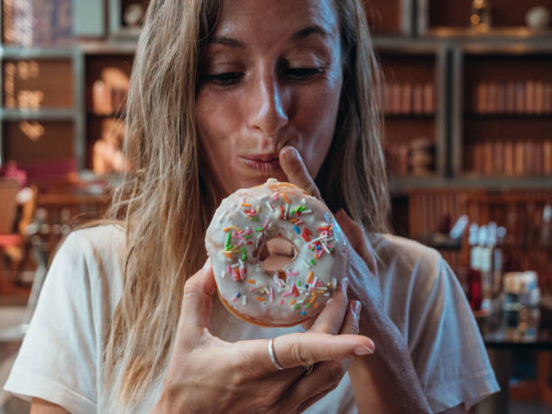 istock Woman eating unhealthy doughnut 1280555736