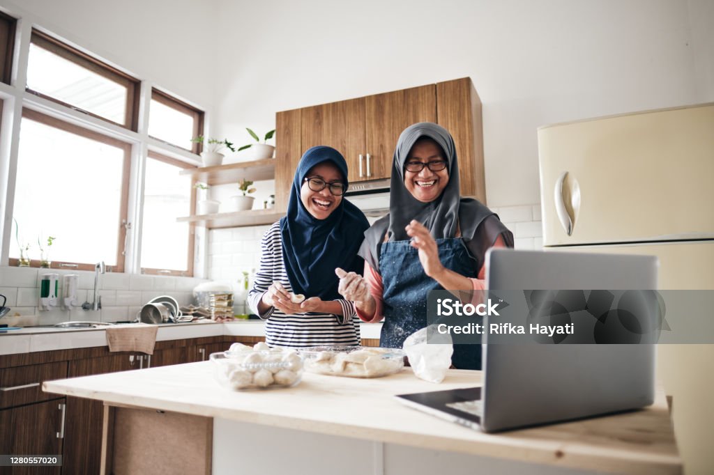 Senior woman doing online communication from home with her daugher Active Senior Cooking Food in The Kitchen Cooking Stock Photo