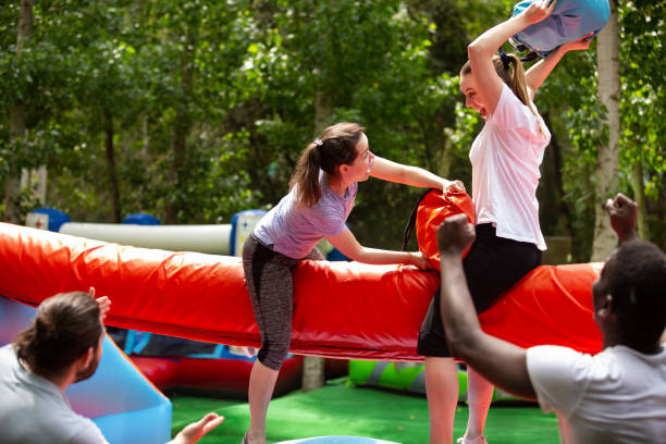 istock Females wrestling by pillows on inflatable log 1280557283