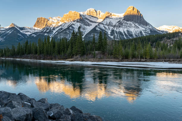 вид на скалистые горы, отраженные в реке боу, кэнмор, канада - rocky mountains canada mountain winter стоковые фото и изображения