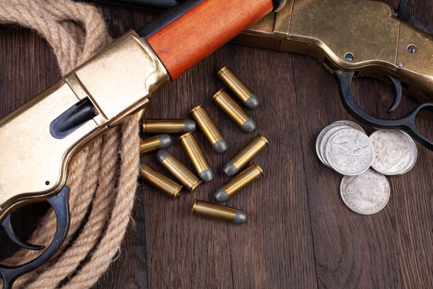 istock Wild west guns - lever-action repeating rifles with ammunition and silver dollar coins 1280558612