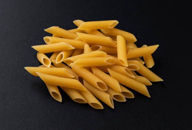 istock Raw penne rigate pasta isolated on black background 1280559590