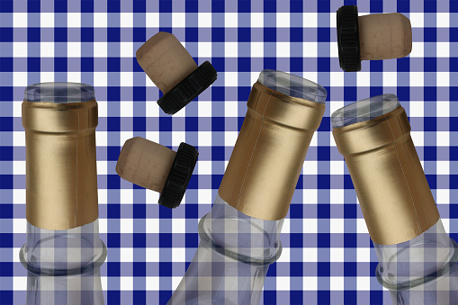 Empty wine bottles and corks lying on blue checkered tablecloth