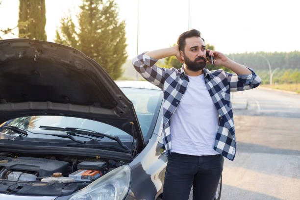 istock Man talking on a cell phone by a broken car 1280563564
