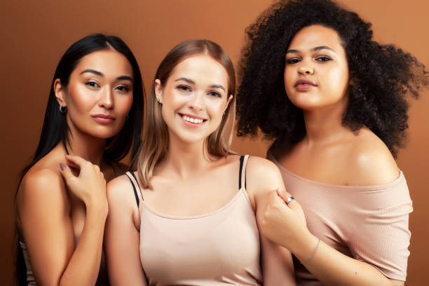 young pretty asian, caucasian, afro woman posing cheerful together on brown background, lifestyle diverse nationality people concept stock photo