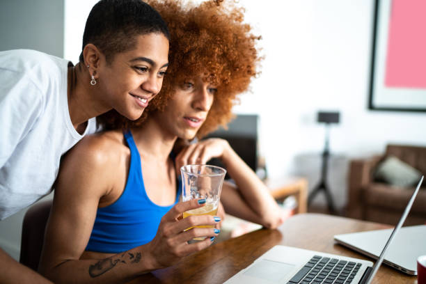 Couple / Friends doing a virtual happy hour at home or watching a video on laptop Couple / Friends doing a virtual happy hour at home or watching a video on laptop transgender person stock pictures, royalty-free photos & images