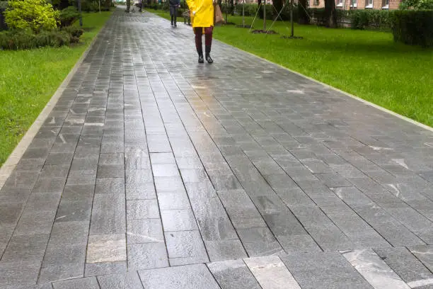 Wet gray path just after rain. People legs walking.