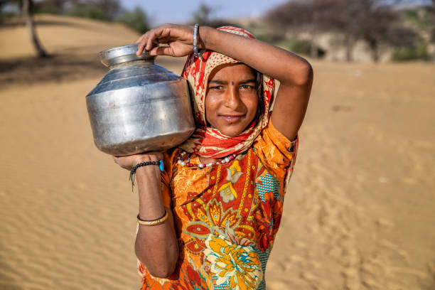 verticale de jeune fille indienne portant l’eau du puits, village de désert, inde - porter sur la tête photos et images de collection