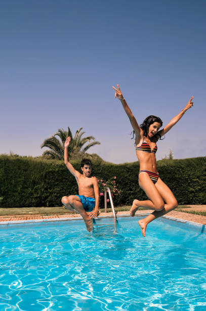istock Young couple having fun jumping in the pool 1280591000