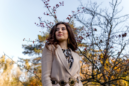 Fashion beauty portrait of young girl poses on the park. Wearing stylish look, looking at the side.