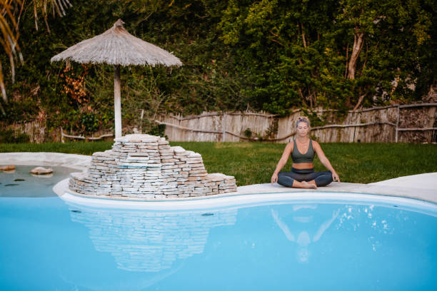 istock Young woman meditating at the pool 1280594551