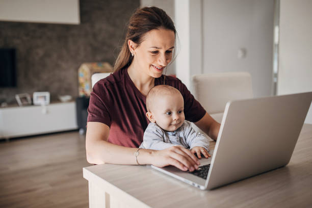 istock Beautiful mother using laptop while holding her baby boy 1280597228