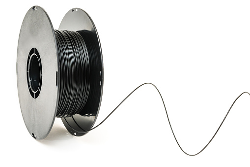 3D Printer Plastic Filament. Spool of black thermoplastic wire for 3D printing close up isolated on white background
