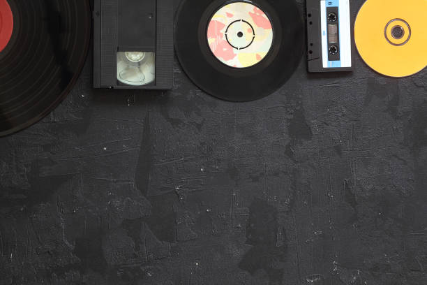 istock Musical storage devices and copy space. Old audio cassette tapes, compact disc and vinyl record on white wooden background with text space. 1280622141