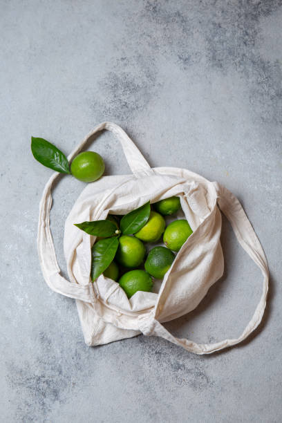 istock Ripe limes with fresh lime tree leaves in eco linen bag. top view 1280627125