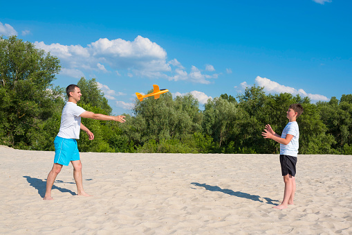 Boy and father play games on the beach on a sunny day. Active rest, lifestyle.