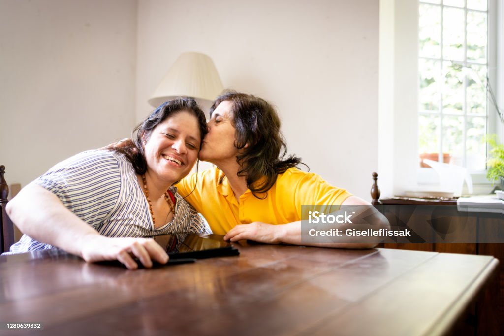 Mother and daugther talking and usin digital tablet in a table Shot of two women sitting and using digital tablet in a table Mother Stock Photo