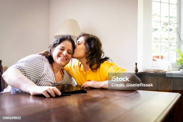 Mother And Daugther Talking And Usin Digital Tablet In A Table Stock Photo - Download Image Now