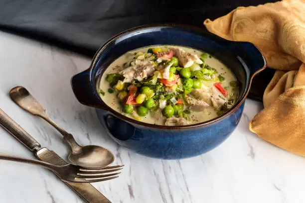 British slow cooked chicken thigh fricassee stew in white sauce with colorful vegetables
