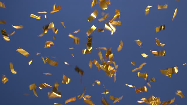 Fireworks made of golden confetti on blue background. 4K 30fps ProRes 4444