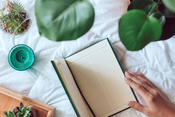 istock Blank notebook lying on bed, succulents and plants on white blanket, top view, cozy home flat lay 1280643933