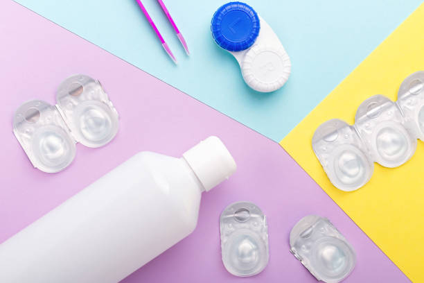 Contact lens kit with bottle of lens solution, case, tweezer on multicolor background, flat lay, top view