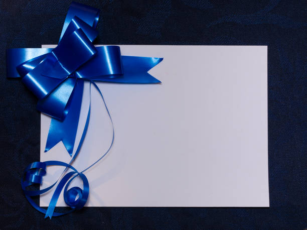 istock White card close up with classic blue gift bow on blue cloth background. Celebration, Christmas, Mother's day, Father's day or invitation concept. 1280644843