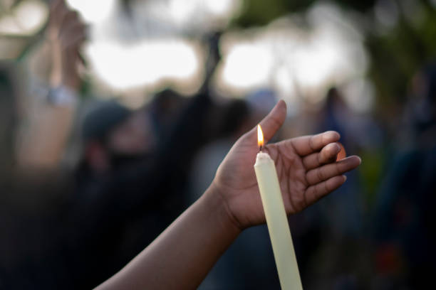 Black hand cups a candle flame at a peace vigil Black hand cups a candle flame at a peace vigil in San Diego, CA, United States memorial vigil stock pictures, royalty-free photos & images