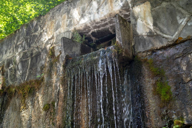 istock Close up of mountain stream flowing from rock in summertime. Manmade decorative waterfall flows down 1280657982