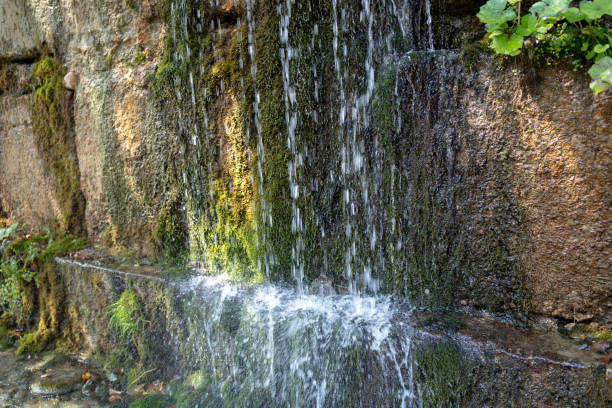 istock Close up of mountain stream flowing down in summertime. Manmade decorative waterfall flows on rock and splashes 1280658049