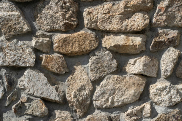 texture of old stones of various forms with seams. close up of shabby masonry. stone wall from uneven different ancient friable cobblestones - friable imagens e fotografias de stock