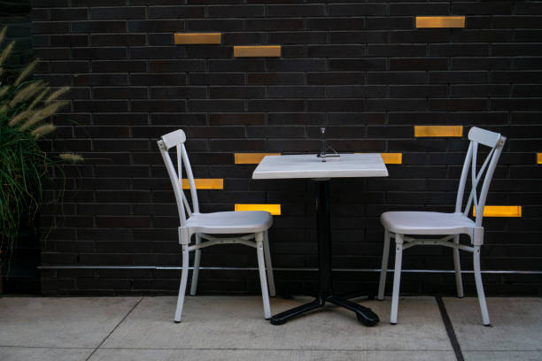 A table and white chairs set up for two people under social distancing rules during the covid-19 pandemic at a sidewalk cafe