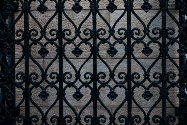 black iron fence with a forged pattern against a wall background