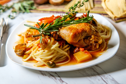 Italian chicken Cacciatore hunter's stew with spaghetti noodles and crusty bread