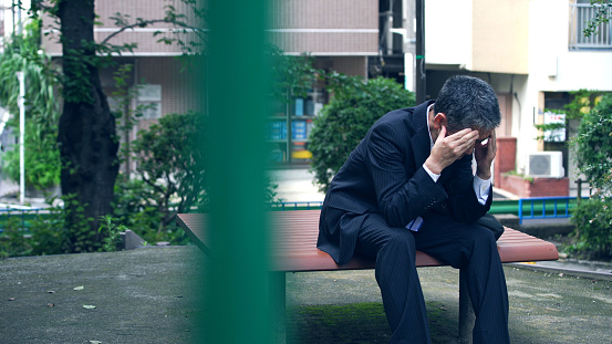 Depressed asian businessman sitting on a bench.