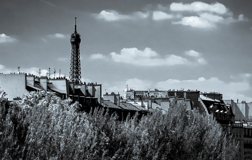 The tip of the Eiffel Tower emerging behind the Paris city roof tops
