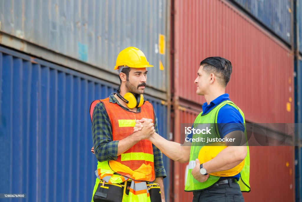 Engineer and worker soul brother handshake, thumb clasp handshake or homie handshake with blurred containers cargo background, Success and Teamwork concept 20-24 Years Stock Photo