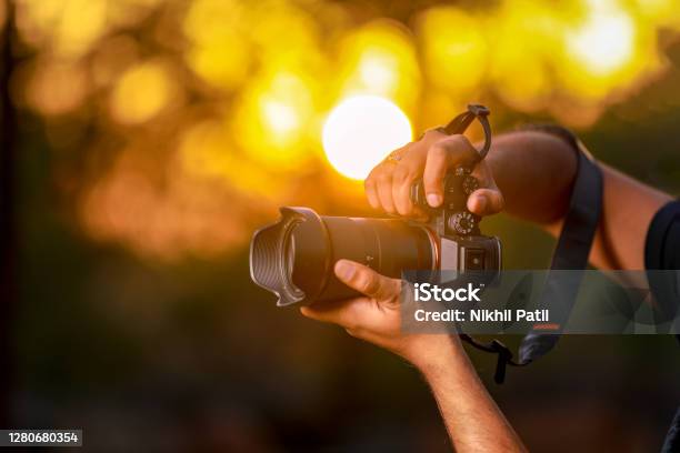 Jalgaon Maharashtra India May 4 2020 Closeup Of A Black Camera Holding By Photographers Hand With Sunset Background Stock Photo - Download Image Now