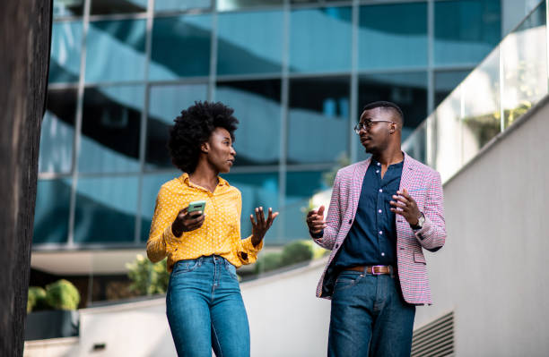 hipsters, joven afroamericana tiene una conversación con su socio frente al edificio. - business two people talking building exterior fotografías e imágenes de stock