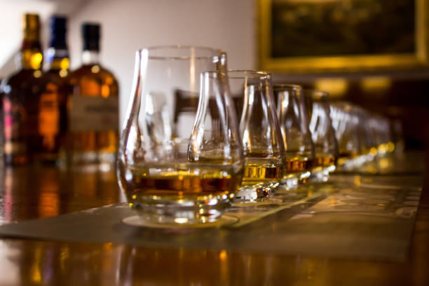 A line of whisky tasting glasses A line of tasting glasses filled with different types of Whiskies for tasting, with the focus on the second glass, the rest is out of focus scotch whisky stock pictures, royalty-free photos & images