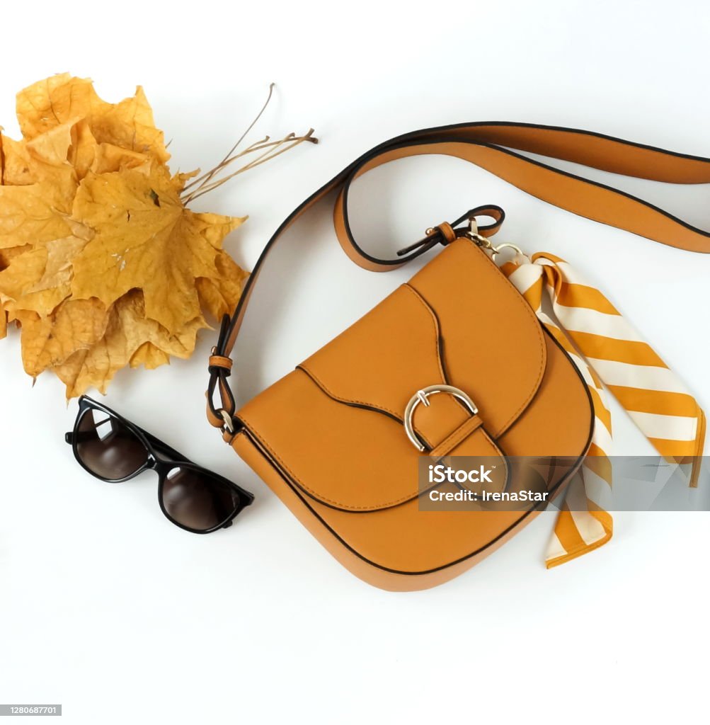 Women fashion clothes and accessories top view on white background. Flat lay collage of female autumn style look with  bag, sunglasses, autumne leaves.Copy space Autumn Stock Photo