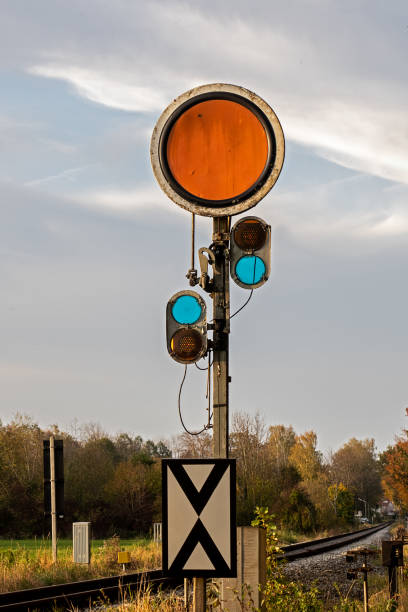 orange sign and blue yellow lights on next to the tracks