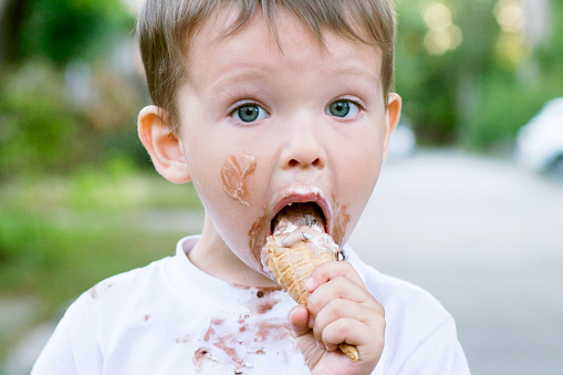 A beautiful little girl in a pretty pink dress eating ice-cream